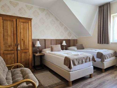 a bedroom with two beds and a chair and a couch at Tokaj Zlatá Putňa - Restaurant & Pension in Viničky