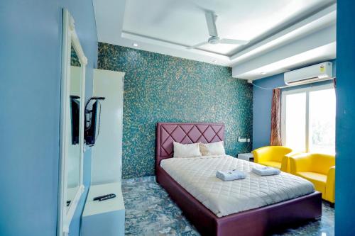 a bedroom with a pink bed and a yellow chair at Hotel Rieejh in Nāgercoil
