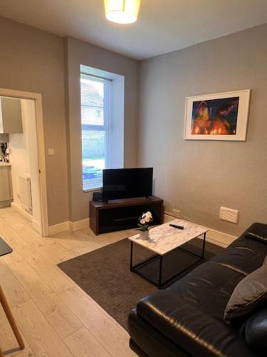 a living room with a couch and a table at Kelpies Serviced Apartments- Robertson in Falkirk