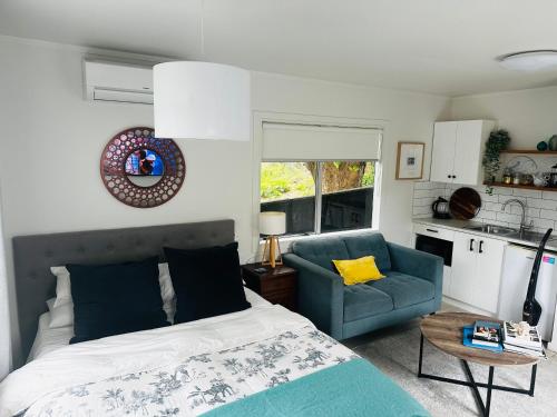 a bedroom with a bed and a blue chair at Private Beachside Studio with Courtyard and Sea view in Paraparaumu