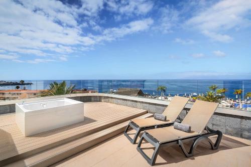 a balcony with two chairs and a bath tub on a deck at Barceló Santiago - Adults Only in Puerto de Santiago