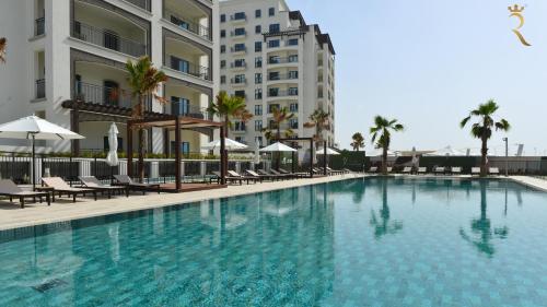 a swimming pool with chairs and umbrellas next to a building at Stylish Yas Studio- Modern Urban Stay in Abu Dhabi
