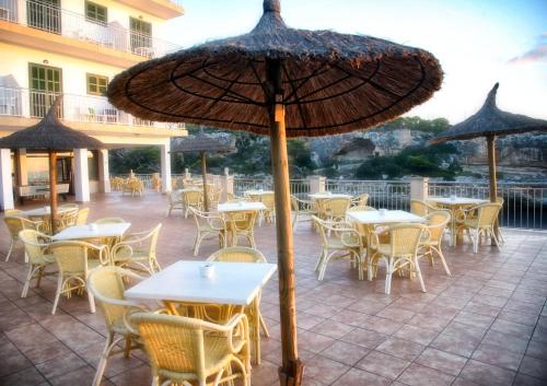
a patio area with tables, chairs and umbrellas at Hotel Villa Sirena in Cala Figuera
