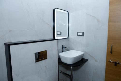 a bathroom with a white sink and a mirror at Pearl Inn in Dhārwād