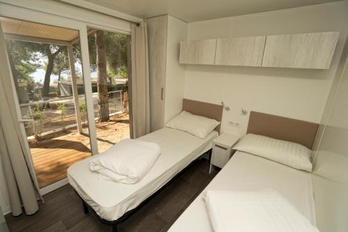 a small room with two beds and a window at Mobile Homes Camping Kovačine in Cres
