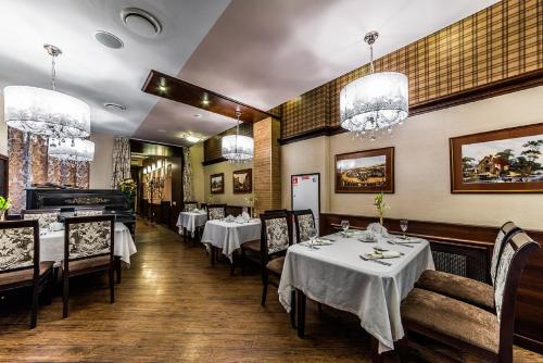 una sala da pranzo con tavoli, sedie e lampadari a braccio di Cronwell Inn Stremyannaya a San Pietroburgo