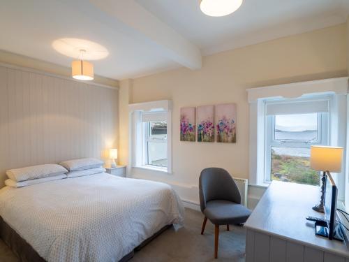 a bedroom with a bed and a chair and two windows at The Convent Leenane in Leenaun