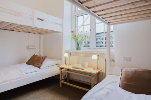 a bedroom with two beds and a table with two lamps at Nomad City Hotel - Odense in Odense