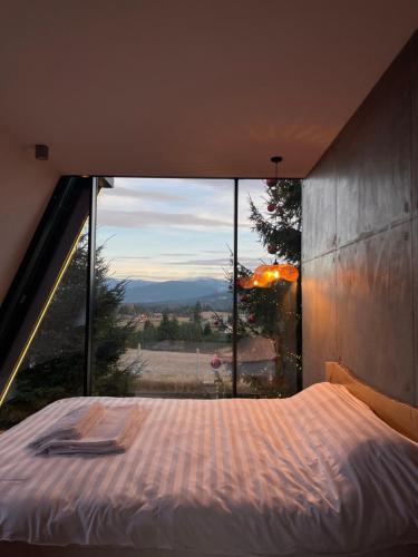 a bed in a room with a large window at TwoTop-Premium Chalet Villa with mountain view in Piatra Fantanele