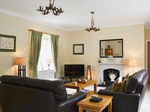 a living room with a couch and a table at Ladybird Cottage in Lochend