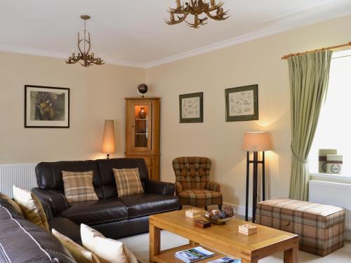 a living room with a couch and a table at Ladybird Cottage in Lochend