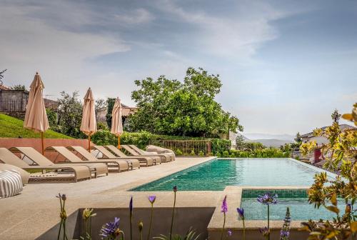 a swimming pool with lounge chairs and umbrellas at Casa da Lameira Douro Valley in Peso da Régua