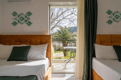 two beds in a room with a view of a balcony at Chrissi Ammoudia in Toroni
