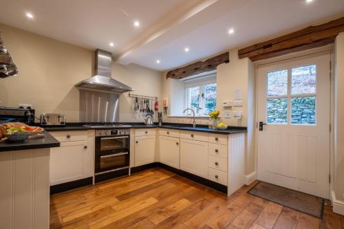 a kitchen with white cabinets and black counter tops at Rose Barn in Hawkshead