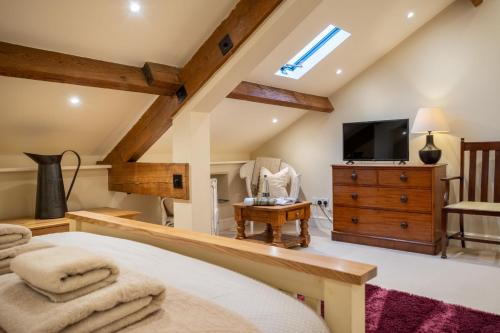 a bedroom with a bed and a tv and a chair at Rose Barn in Hawkshead