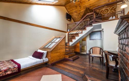 a living room with a staircase and a bed at Summit Grace Boutique Hotel & Spa in Darjeeling
