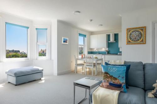 a living room with a blue couch and a kitchen at Rooftop Hideaway -Central Coastal Flat - Sea Views in Seaton