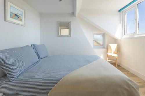 a bedroom with a large bed with two windows at Rooftop Hideaway -Central Coastal Flat - Sea Views in Seaton