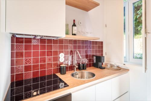a kitchen with a sink and red tiles on the wall at Casa da Lameira Douro Valley in Peso da Régua