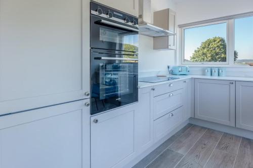 a kitchen with white cabinets and a large window at River View - Prime River Front Location in Seaton