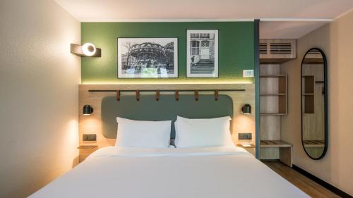 a bedroom with a large bed and a green wall at Campanile NATURE - Strasbourg Sud Geispolsheim in Geispolsheim