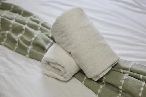 a roll of white towels on a bed at Hayy Vibrant Studios Queensgate in Huddersfield