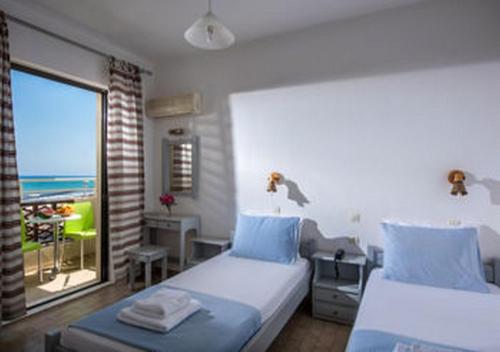 a bedroom with two beds and a view of the ocean at Smaragdine Beach Hotel in Stalís