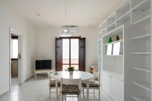 a white dining room with a white table and chairs at San Menaio Apartment by Rentbeat in San Menaio
