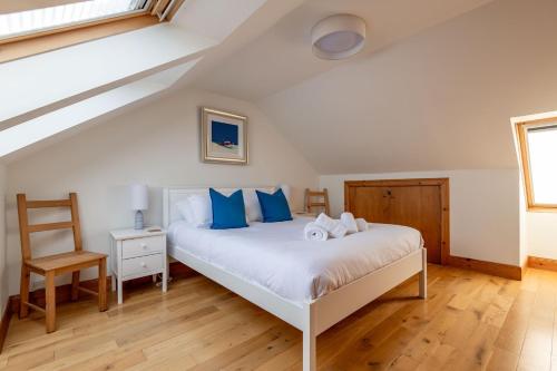 a bedroom with a bed with blue pillows and a chair at Dylsford - Elie in Elie