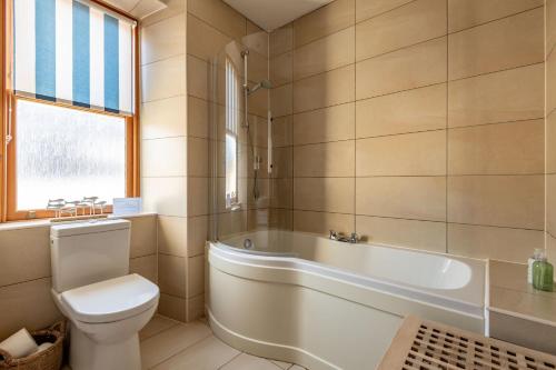 a bathroom with a tub and a toilet and a sink at Dylsford - Elie in Elie