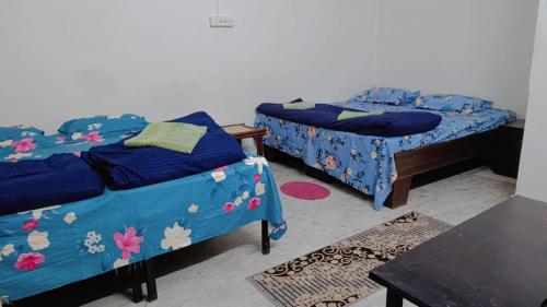 a room with two beds and a table with rugs at Homestay Urmil Basant in Jaipur