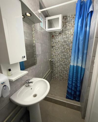 a bathroom with a sink and a blue shower curtain at Hotel Etno Selo Timcevski in Kumanovo