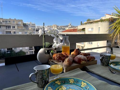 a table with a breakfast of orange juice and pastries on a balcony at Appartement spacieux - Vue notre dame de la garde - Terrasse - Wifi in Marseille