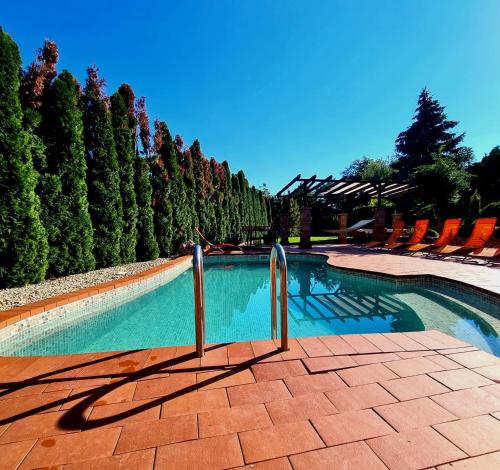 a swimming pool with chairs and trees in the background at Relax Holiday House in Balatonrendes