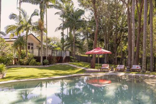 a swimming pool with a red umbrella and two chairs at Sunrise Guesthouse in Byron Bay