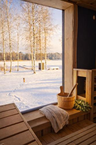 a window in a cabin looking out at a snow covered field at Berzkrasti Lake House with Private Sauna & Beach in Sigulda