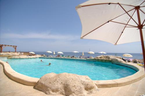 a swimming pool with an umbrella and people in the water at The Preluna Hotel in Sliema
