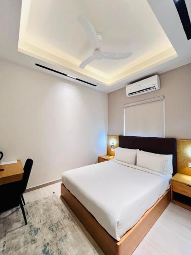 a bedroom with a large white bed and a desk at Central Residence by Paramount Hospitality in Karachi