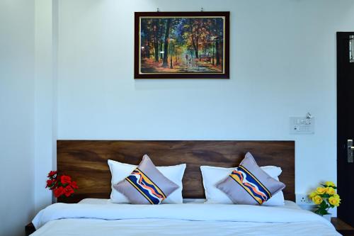 a bed with white pillows and a painting above it at Hotel Parineeta in Khagaria