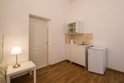 a small white kitchen with a table and a lamp at White Amber in Liepāja