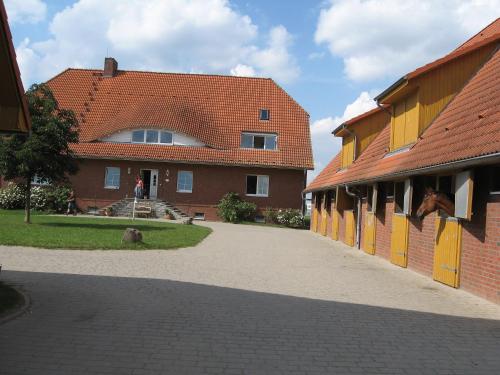 a brick building with a red roof and a walkway at Pferdehof Ruhnau in Potzlow