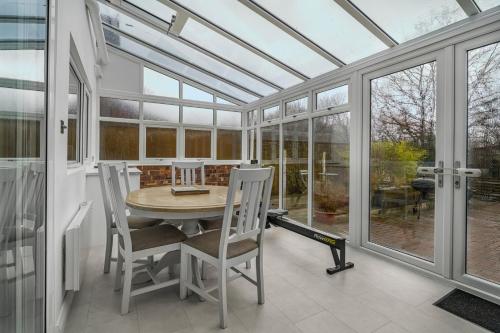 a conservatory with a table and chairs and windows at GuestReady - Tranquil Retreat near Bramall Hall in Cheadle