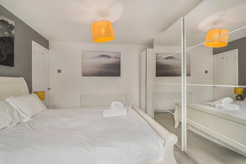 a white bedroom with a bed and two shelves at GuestReady - Tranquil Retreat near Bramall Hall in Cheadle