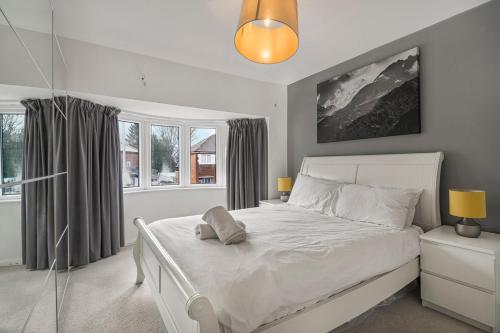 a bedroom with a large white bed and windows at GuestReady - Tranquil Retreat near Bramall Hall in Cheadle
