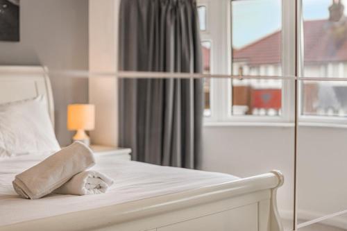 a white bedroom with a bed with a window at GuestReady - Tranquil Retreat near Bramall Hall in Cheadle