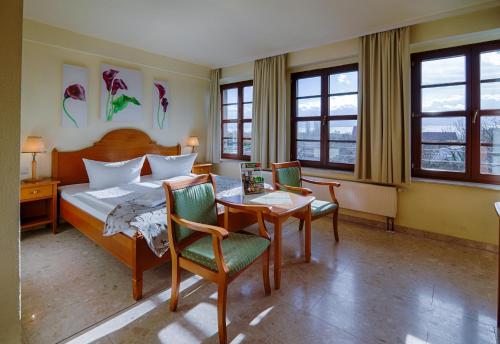 ルターシュタット・ヴィッテンベルクにあるホテル ブラウハウス ヴィッテンベルクのベッド、テーブル、椅子が備わるホテルルームです。