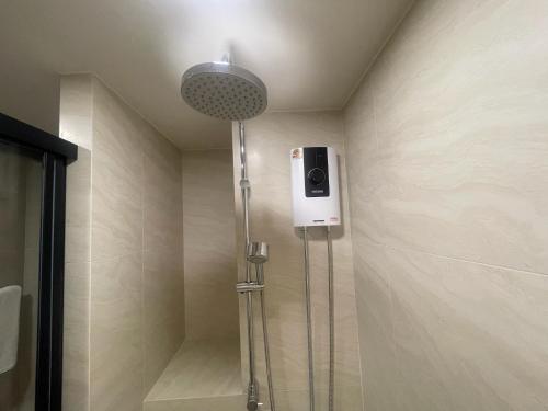 a shower in a bathroom with a phone on the wall at Rest&Rise Phuket in Ban Rangeng