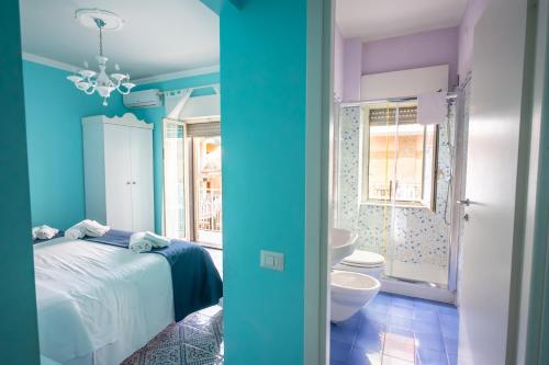 a blue bedroom with a bed and a bathroom at Hotel Villa Nefele in Giardini Naxos