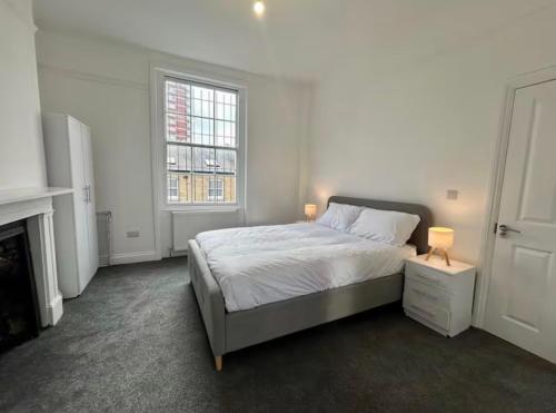 a white bedroom with a bed and two lamps at The 402 Residence in London