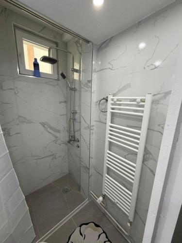a bathroom with a shower with white marble walls at Apartman AURORA Trstenik in Trstenik